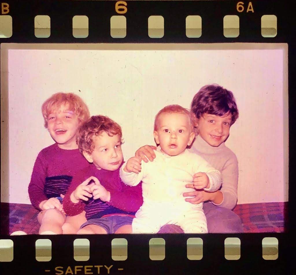 Four siblings sitting together in a vintage scanned family photo.